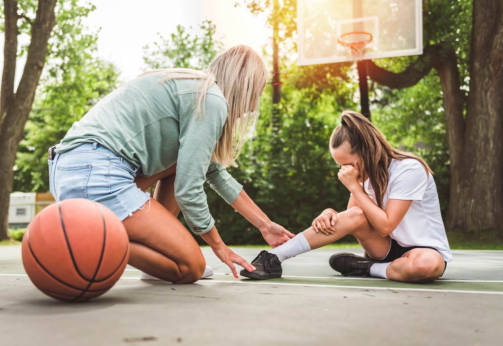 Mother assisting injured daughter on the basketball court