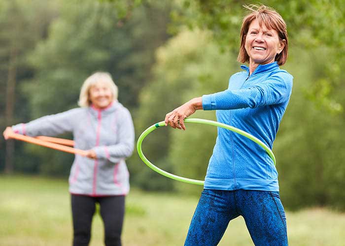 Two women hula hooping in a park