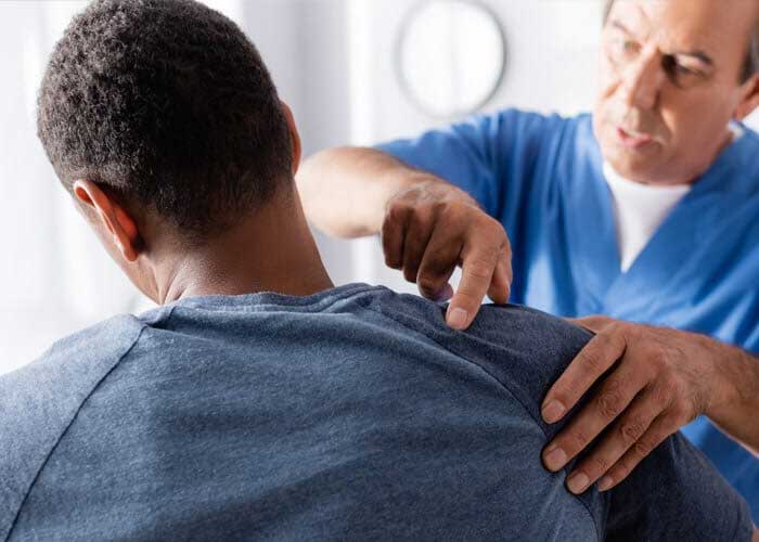 Physician examining shoulder of patient
