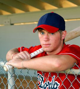 Teen baseball player holding a bat in the dugout