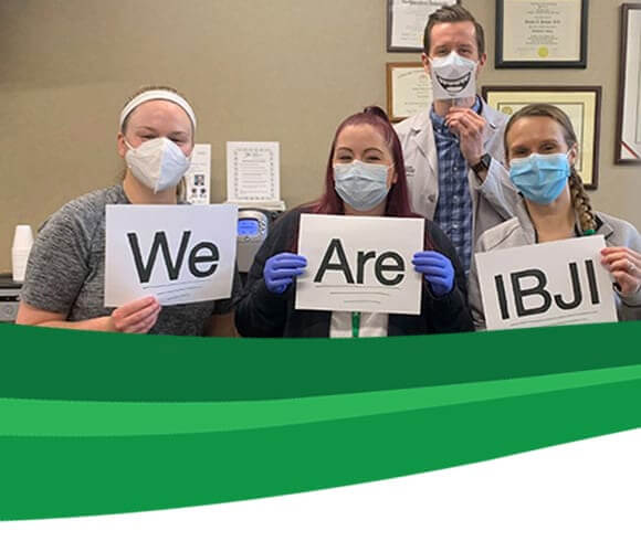 Team members holding "We Are IBJI" sign